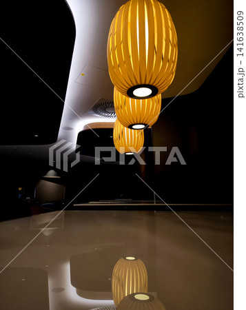 Close up of modern wooden pendant lights with warm ambient glow in stylish Munich conference hotel interior, contemporary lighting design detail against dark background in hospitality space Close up of modern wooden pendant lights with warm ambient glow in stylish Munich conference hotel interior, contemporary lighting design detail against dark background in hospitality space 141638509
