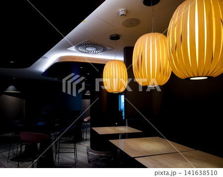 Modern lounge seating area with contemporary pendant lights in stylish conference hotel interior, cozy corner with upholstered bench, round tables and design armchair, warm ambient lighting in busines Modern lounge seating area with contemporary pendant lights in stylish conference hotel interior, cozy corner with upholstered bench, round tables and design armchair, warm ambient lighting in busines 141638510