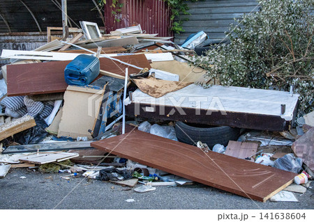 Mixed trash and debris on street - illegal waste disposal and environmental issue. Illegal dumping of household waste and furniture - urban pollution and environmental problem Mixed trash and debris on street - illegal waste disposal and environmental issue. Illegal dumping of household waste and furniture - urban pollution and environmental problem 141638604