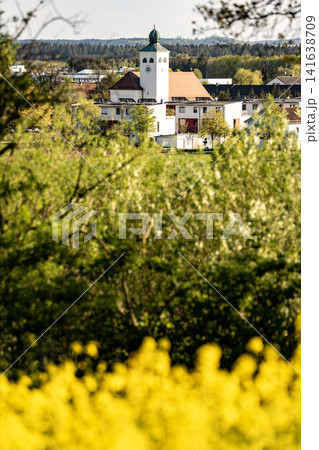 Vibrant Yellow Rapeseed Field With Gilching Village Church In Background - Bavarian Countryside Spring Landscape, Blooming Canola, Rural Bavaria Germany, Soft Bokeh Vibrant Yellow Rapeseed Field With Gilching Village Church In Background - Bavarian Countryside Spring Landscape, Blooming Canola, Rural Bavaria Germany, Soft Bokeh 141638709