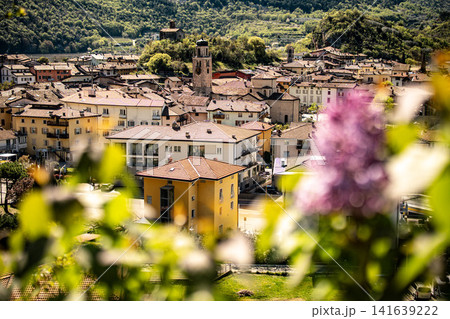 Elevated View Over Nago Town With Foreground Flowers: Scenic Hillside Landscape Near Lake Garda In Province Of Trento Italy Elevated View Over Nago Town With Foreground Flowers: Scenic Hillside Landscape Near Lake Garda In Province Of Trento Italy 141639222