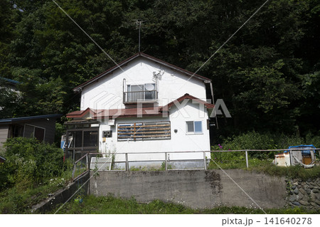 緑豊かな山あいにひっそりと佇む誰も住まなくなった白い家 緑豊かな山あいにひっそりと佇む誰も住まなくなった白い家 141640278