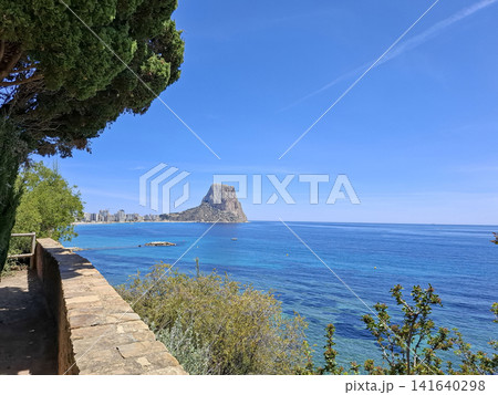 Panoramic view of Penon de Ifach rock mountain from coastal promenade in Calpe Spain on a clear day Panoramic view of Penon de Ifach rock mountain from coastal promenade in Calpe Spain on a clear day 141640298