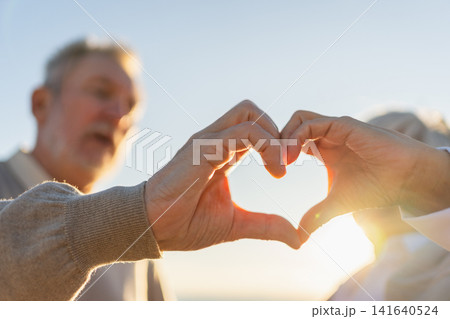 Love heart shape peace. Senior older couple making heart shape with their hands. Adult mature old husband wife showing heart sign. Happy pensioner family. I love you happy valentines day Love heart shape peace. Senior older couple making heart shape with their hands. Adult mature old husband wife showing heart sign. Happy pensioner family. I love you happy valentines day 141640524