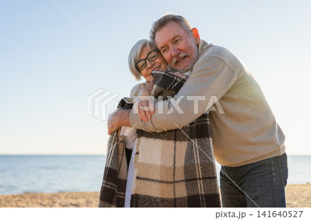 Senior mature couple hugging enjoying outdoor recreation walking on beach. Old husband wife embracing with tenderness love enjoying sweet bonding. Grandmother grandfather together. Family moment love Senior mature couple hugging enjoying outdoor recreation walking on beach. Old husband wife embracing with tenderness love enjoying sweet bonding. Grandmother grandfather together. Family moment love 141640527