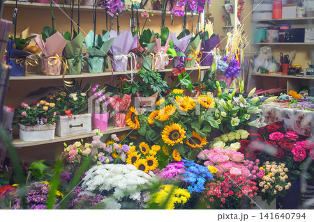 Colorful flower display with sunflowers, roses, orchids, seasonal bouquets inside florist shop. Abundant floral assortment, retail, small business, gift shopping 141640794
