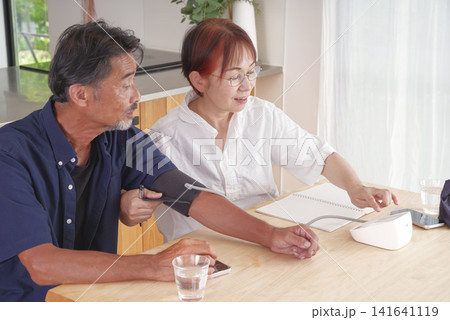 血圧計を使って健康管理をする熟年夫婦 血圧計を使って健康管理をする熟年夫婦 141641119
