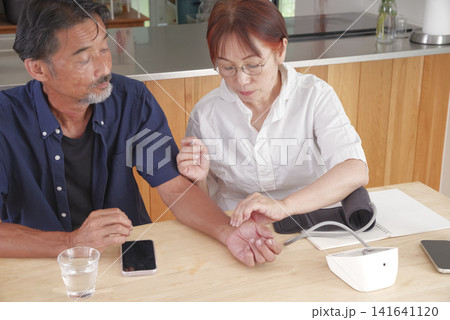 血圧計を使って健康管理をする熟年夫婦 血圧計を使って健康管理をする熟年夫婦 141641120