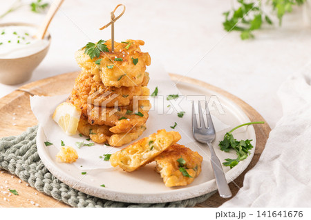 Delicious golden cod fritters on a plate with dipping sauce and fresh parsley garnish perfect as a tasty Mediterranean seafood appetizer snack Delicious golden cod fritters on a plate with dipping sauce and fresh parsley garnish perfect as a tasty Mediterranean seafood appetizer snack 141641676