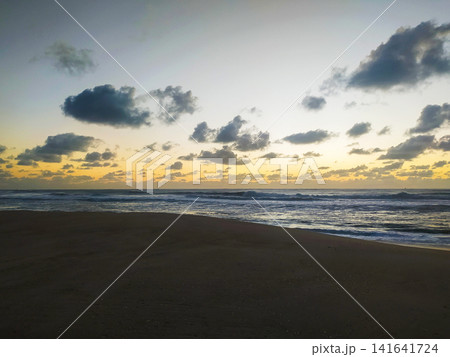Captivating sunrise over a tranquil beach with rolling ocean waves and dramatic clouds. This serene coastal landscape is perfect for travel, wellness, and environmental themes. Purely stunning. Captivating sunrise over a tranquil beach with rolling ocean waves and dramatic clouds. This serene coastal landscape is perfect for travel, wellness, and environmental themes. Purely stunning. 141641724