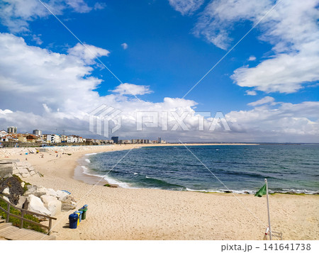 A scenic wideangle view of a golden sandy beach curving along the deep blue ocean water under a vibrant sky with white clouds, evoking a peaceful sense of coastal serenity and summer bliss. A scenic wideangle view of a golden sandy beach curving along the deep blue ocean water under a vibrant sky with white clouds, evoking a peaceful sense of coastal serenity and summer bliss. 141641738