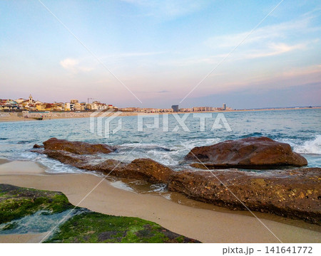 Serene coastal landscape at sunset with nobody. Gentle ocean waves crash over rocky shore, offering a tranquil sense of peace. Perfect for travel, wellness, and nature concepts. 141641772