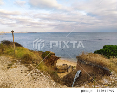 A coastal view from a cliff edge overlooking the ocean with nobody in sight. The rugged landscape and signpost evoke a sense of peaceful solitude, perfect for themes of travel, nature, and escape. 141641795