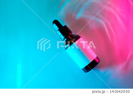 Cosmetics serum dropper bottle floating in neon water Cosmetics serum dropper bottle floating in neon water 141642030