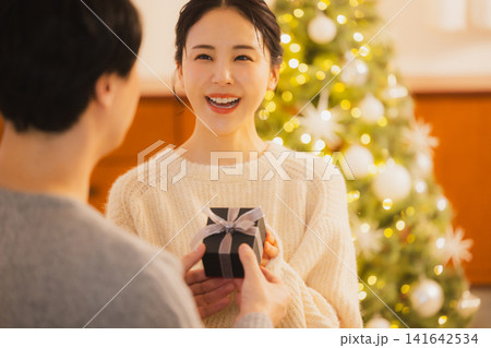 クリスマスプレゼントを渡す若いカップル クリスマスプレゼントを渡す若いカップル 141642534