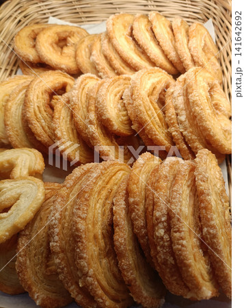 Sweet pastry, sugar, wicker basket, golden baked puff pastry arranged in rows 141642692