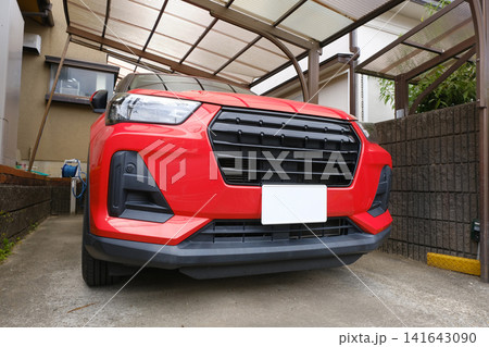 （左下アングル）戸建て住宅のガレージに駐車された赤いコンパクトSUV：マイホームと豊かなカーライフ 141643090