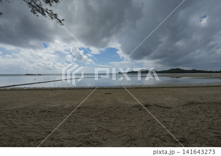 厚い雲の下で鏡のように凪いだ海と砂浜(石垣島) 厚い雲の下で鏡のように凪いだ海と砂浜(石垣島) 141643273