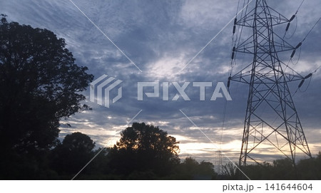 high voltage power line at sunset blue and dark cloud high voltage power line at sunset blue and dark cloud 141644604