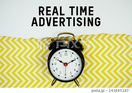 Real Time Advertising text written on paper with alarm clock on yellow chevron background Real Time Advertising text written on paper with alarm clock on yellow chevron background 141645187