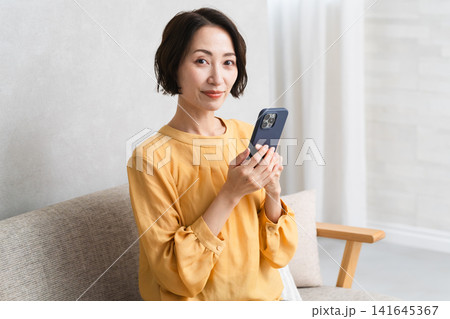 スマートフォンを操作する女性 ライフスタイルイメージ スマートフォンを操作する女性 ライフスタイルイメージ 141645367