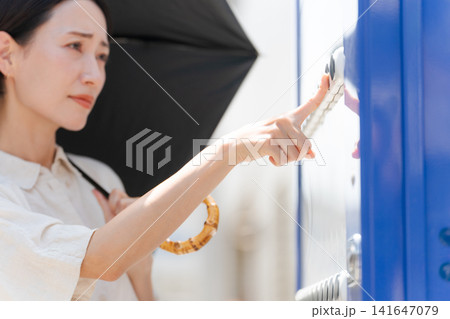 暑い日に自販機で飲み物を買う女性 141647079
