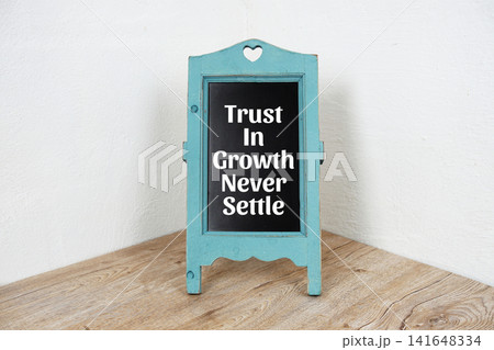 Trust In Growth Never Settle Inspirational And Motivational Quotes written on blue easel Trust In Growth Never Settle Inspirational And Motivational Quotes written on blue easel 141648334