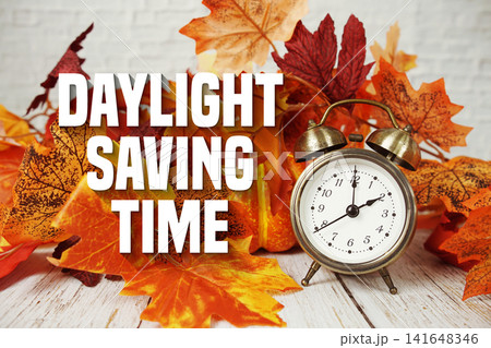 Daylight Saving Time text with alarm clock and maple leaf decoration on wooden background Daylight Saving Time text with alarm clock and maple leaf decoration on wooden background 141648346