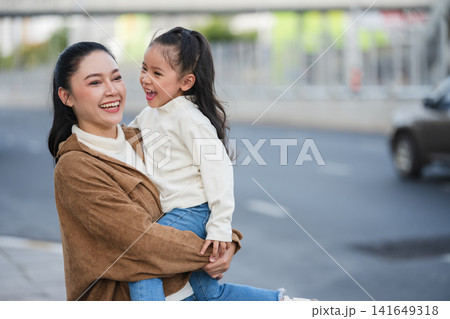 mother holding daughter on city street mother holding daughter on city street 141649318