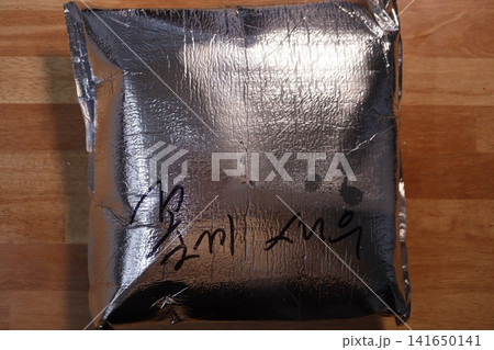 Metallic Foil Package with Korean Text on Wooden Surface Metallic Foil Package with Korean Text on Wooden Surface 141650141