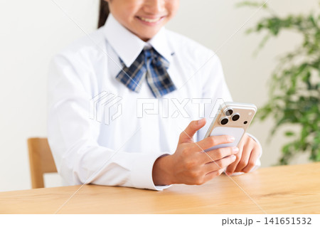リビングのテーブルでスマホを見る制服姿の中学生 リビングのテーブルでスマホを見る制服姿の中学生 141651532
