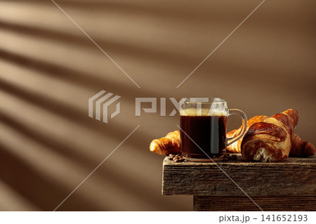 Black coffee with croissants on an old wooden table. Black coffee with croissants on an old wooden table. 141652193