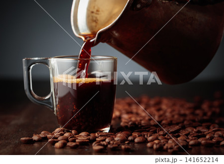 Black coffee is poured into a glass cup. 141652214