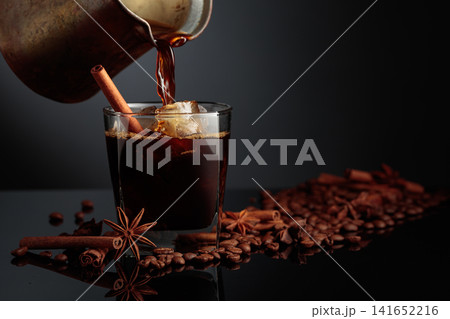 Coffee is poured into a glass with ice. Coffee is poured into a glass with ice. 141652216