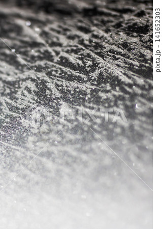 Textured dark surface with scattered white granules under soft angled light, creating high contrast tactile pattern, speckled detail, rough grain, minimal abstract background Textured dark surface with scattered white granules under soft angled light, creating high contrast tactile pattern, speckled detail, rough grain, minimal abstract background 141652303