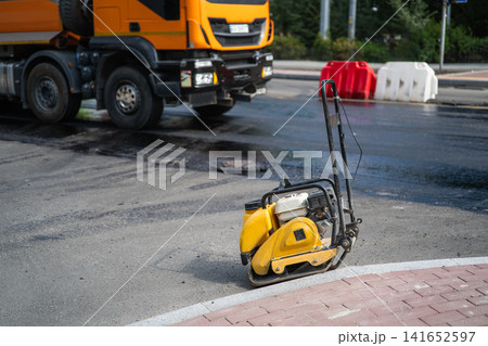 Vibratory plate compactor equipment on street asphalt during road repair Vibratory plate compactor equipment on street asphalt during road repair 141652597