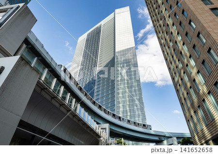 Low-angle view of a New Transit Yurikamome line train running on the elevated track with modern skyscrapers in Shiodome, Minato, Tokyo, Japan. It's an automated guideway transit service in Tokyo. Low-angle view of a New Transit Yurikamome line train running on the elevated track with modern skyscrapers in Shiodome, Minato, Tokyo, Japan. It's an automated guideway transit service in Tokyo. 141652658