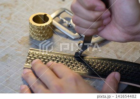 革ベルトにヘリ落とし加工をする職人の手元 革ベルトにヘリ落とし加工をする職人の手元 141654482