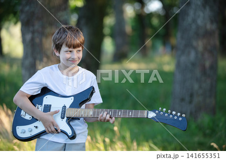 A young boy plays an open air in an open air in a park surrounded by trees on a sunny day. A young boy plays an open air in an open air in a park surrounded by trees on a sunny day. 141655351