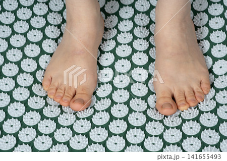Close Up of Bare Feet and Acupressure Therapy Mat 141655493