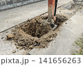 油圧ショベルが舗装道路を掘削し土砂が盛り上がる様子 141656263