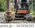 土砂をすくう油圧ショベルとオペレーターが写る工事現場 141656265