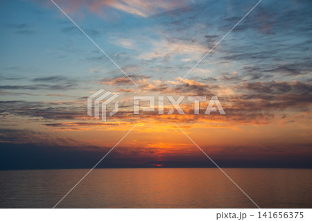 夕暮のオレンジ色の夕焼雲とオレンジ色に反射する海面 夕暮のオレンジ色の夕焼雲とオレンジ色に反射する海面 141656375