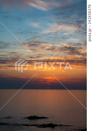 夕暮のオレンジ色の夕焼雲とオレンジ色に反射する海面 141656376