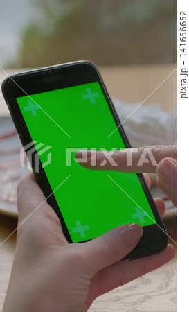 Vertical video. Businesswoman using mobile cell phone with green touch screen in cafe. Green Screen. Vertical video. Businesswoman using mobile cell phone with green touch screen in cafe. Green Screen. 141656652