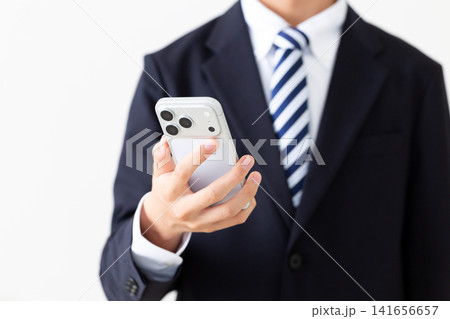 スマホを持つスーツを着た若い男性ビジネスマン スマホを持つスーツを着た若い男性ビジネスマン 141656657