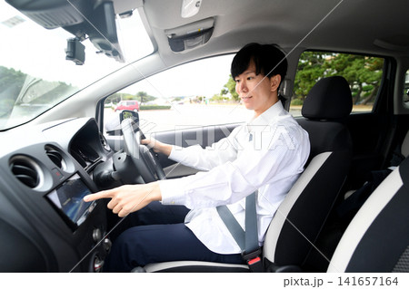 車内でカーナビを操作する若いアジア人男性 141657164