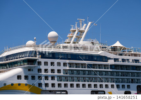 Modern cruise ship with multiple decks and balconies against a clear blue sky Modern cruise ship with multiple decks and balconies against a clear blue sky 141658251