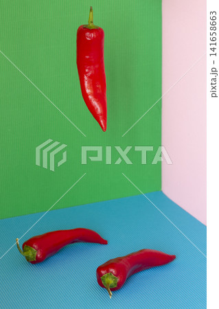 Three red peppers on a colored background Three red peppers on a colored background 141658663