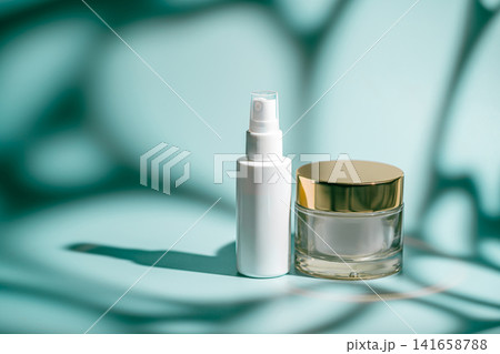 Glass face serum and rich cream jar on blue Glass face serum and rich cream jar on blue 141658788